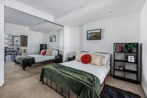 Ein modernes Schlafzimmer mit zwei Betten, einem großen Spiegel und einem Bücherregal.