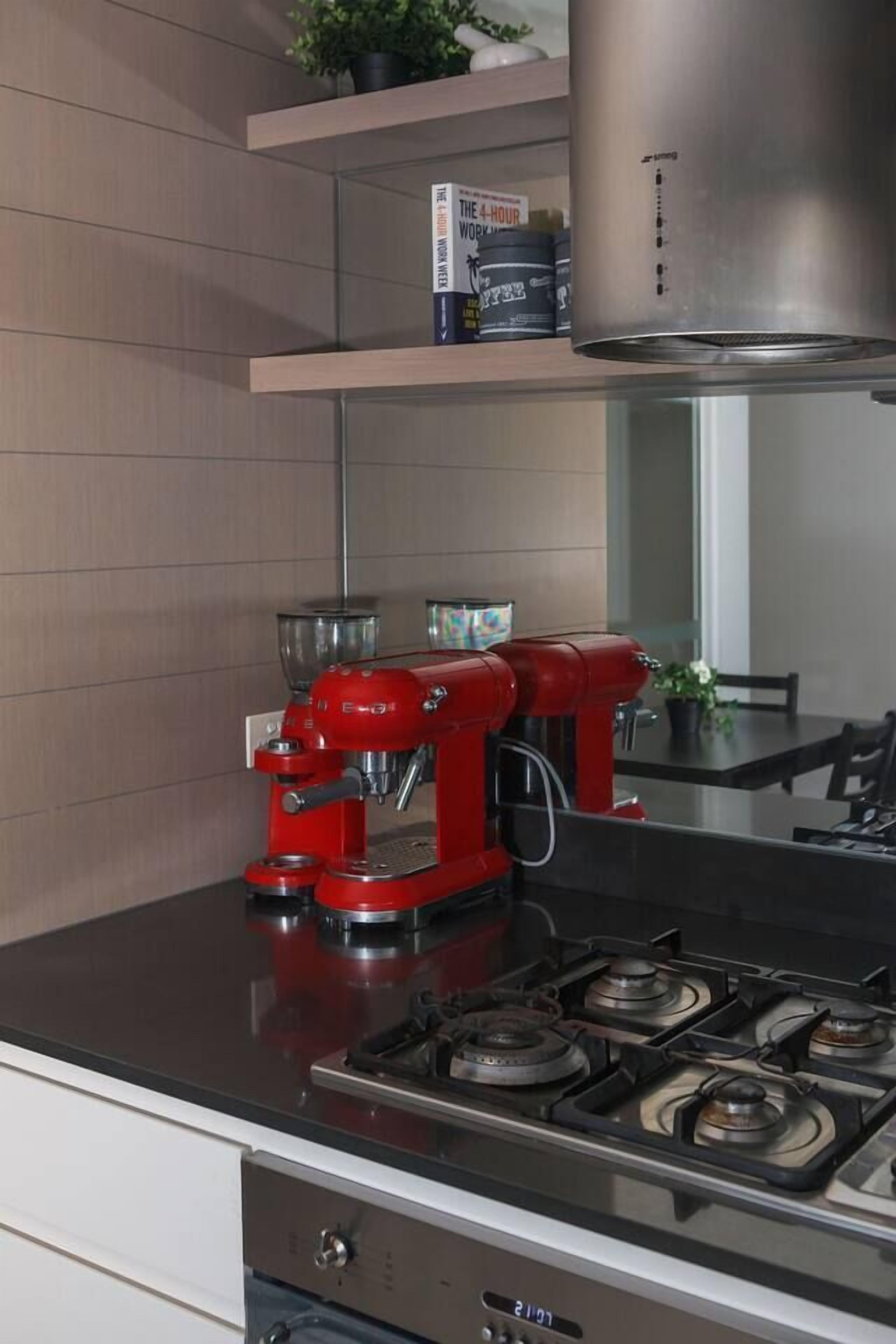 A modern kitchen with a red stand mixer, a stainless steel range hood, and a gas stove.