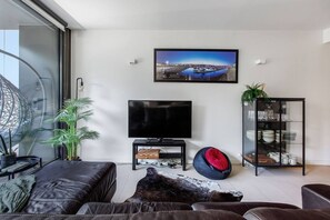 Ein modernes Wohnzimmer mit einem Flachbildfernseher, einer Vitrine mit Geschirr und einem großen Fenster mit Blick auf eine Marina.