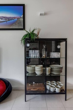 Ein schwarzer Glasschrank mit Regalen, gefüllt mit Tellern, Schüsseln und Tassen.