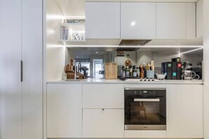 A modern kitchen with built-in appliances, a dishwasher, and a coffee machine. - Urban Escape on Smith Street w Balcony and Parking (Collingwood)