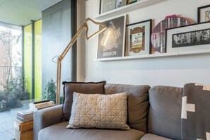 Ein modernes Wohnzimmer mit einer Couch, einer Stehlampe und gerahmten Bildern an der Wand.