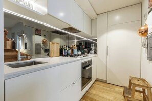 Una cocina moderna con armarios blancos, electrodomésticos de acero inoxidable y una tabla de cortar de madera con la etiqueta 'chop chop'.