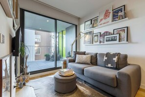 Ein modernes Wohnzimmer mit grauem Sofa, Couchtisch und Bücherregal mit gerahmten Bildern.