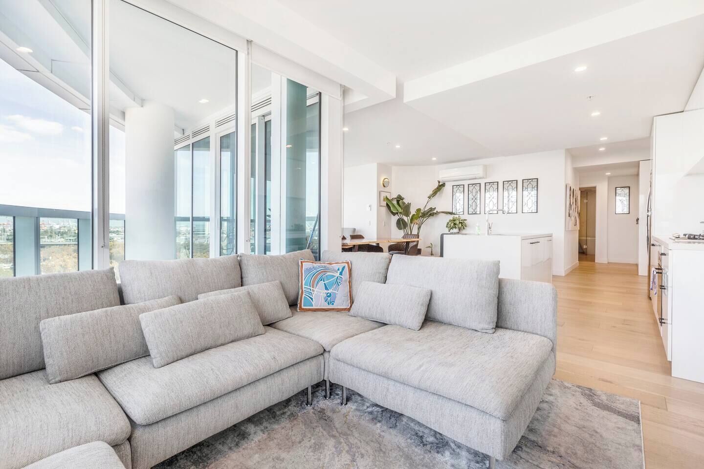 A modern living room with a sectional sofa, a dining area, and a kitchen.
