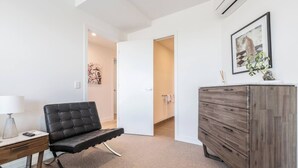 A modern room with a black leather chair, a wooden dresser, and a painting of a leopard. - The Fawn Relish in Sub Penthouse Panorama (North Melbourne)