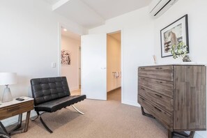 Ein modernes Zimmer mit einem schwarzen Ledersessel, einem Holzkoffer und einem Gemälde von einem Leoparden.