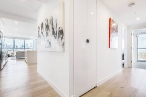 A modern interior with a large abstract painting, a red artwork, and a view of the city through large windows. - The Fawn Relish in Sub Penthouse Panorama (North Melbourne)
