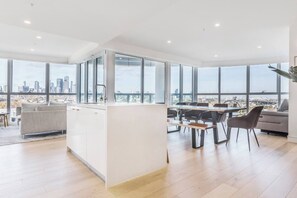 Eine moderne Küche mit großen Fenstern, eine Essecke mit Holztisch und -stühlen und Blick auf die Stadt.