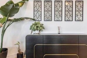 Un comptoir d’accueil avec un revêtement en bois foncé, une plante en pot et un panneau décoratif orné de motifs géométriques.