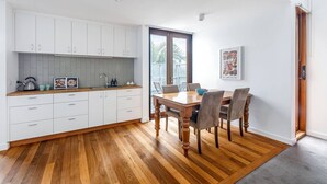 Uma cozinha moderna com armários brancos, bancada de madeira e uma mesa de jantar com cadeiras.