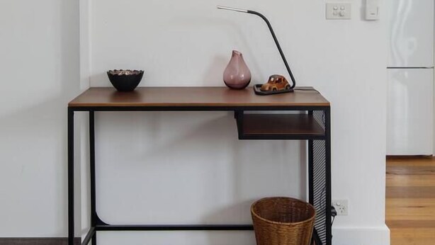 Quarto minimalista com uma escrivaninha, uma obra de arte na parede de cabeça de veado, um vaso e um carrinho de brinquedo.