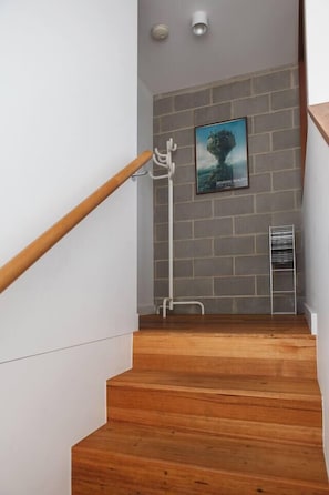 Eine Holztreppe mit weißer Handlauf, eine graue Ziegelwand und ein Plakat an der Wand.