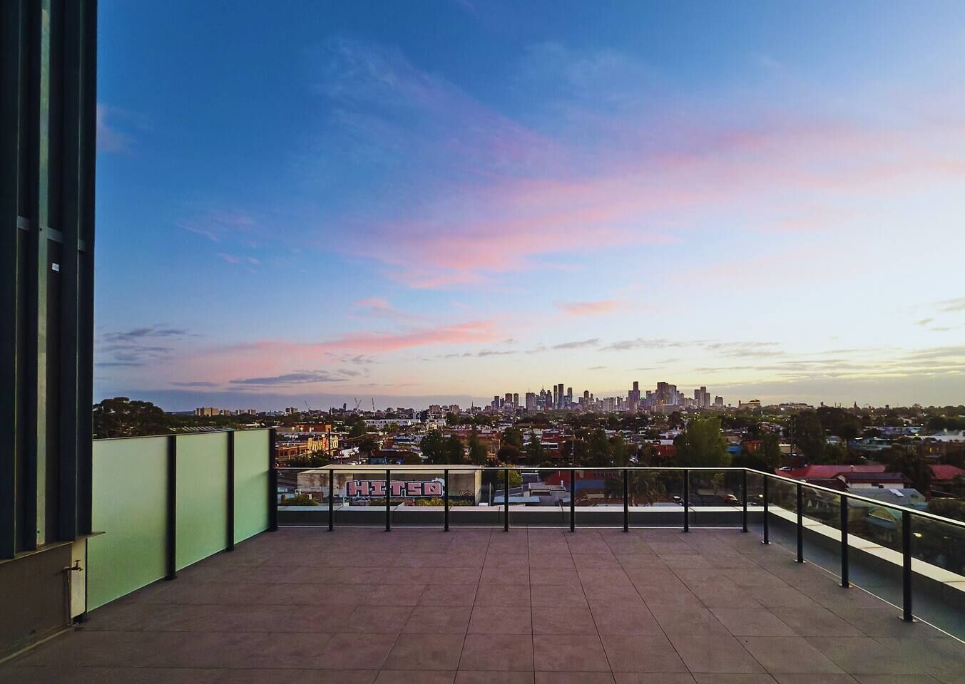 Un balcon offrant une vue sur la ville au coucher du soleil.