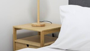 A bed with a white pillow and a wooden bedside table with a lamp. - Northside Rendezvous A Stylish Couples Hideaway (Brunswick East)