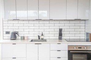 Una cocina moderna con armarios blancos, horno de acero inoxidable y salpicadero de azulejos.