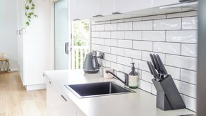 A modern kitchen with white cabinets, a black kettle, a coffee maker, and a knife block.