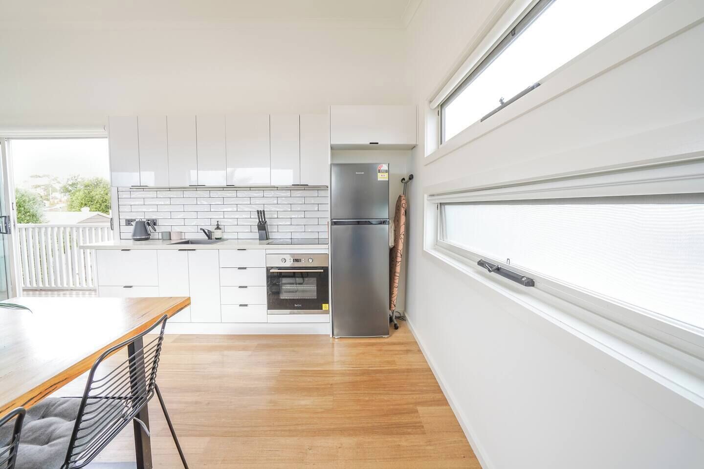 A modern kitchen with white cabinets, a stainless steel refrigerator, and a built-in oven.