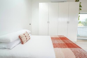 A bedroom with a bed, white walls, a white wardrobe, and a window with a view. - Charming Highton Hideaway between CBD and Surf Coast (Highton)
