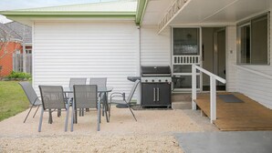 A patio with a grill, outdoor seating, and a covered area with a staircase. - Breezy Beach Shack Footsteps to Sand and Surf (Ocean Grove)
