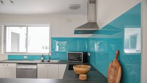 A modern kitchen with a dishwasher, microwave, and wooden bowl on the counter. - Breezy Beach Shack Footsteps to Sand and Surf (Ocean Grove)