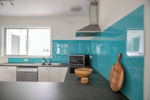 Eine moderne Küche mit Geschirrspüler, Mikrowelle und einer Holtschale auf der Arbeitsfläche.