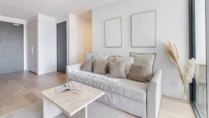 A modern living room with a sofa, a coffee table, and two framed artworks on the wall. - Perched on Parkville A Minimalist Retreat w Pool (Parkville)