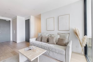 A modern living room with a sofa, a coffee table, and two framed artworks on the wall. - Perched on Parkville A Minimalist Retreat w Pool (Parkville)