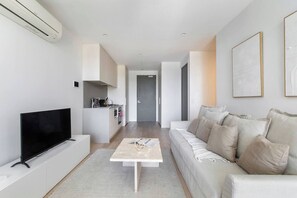 A modern living room with a flat-screen TV, a coffee table, and a sofa. - Perched on Parkville A Minimalist Retreat w Pool (Parkville)