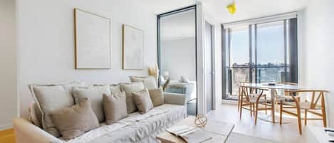 A modern living room with a sofa, a coffee table, and a dining area with chairs.