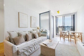 Un salon moderne comprenant un canapé, une table basse et un coin repas avec des chaises.