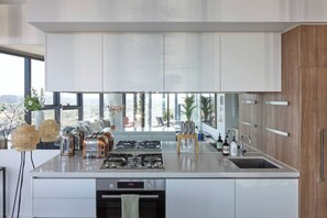A modern kitchen with a large island, stainless steel appliances, and a view of the city. - Panoramic Elegance Stylish off Chapel St with Pool (South Yarra)