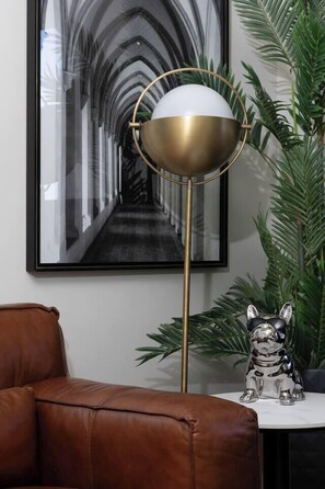 A framed photograph of a corridor, a modern floor lamp, a brown leather chair, and a small metallic dog figurine on a table. - Citylight Haven Urban Comfort near Melbourne Icons (West Melbourne)