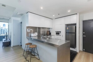 A modern kitchen with a central island, stainless steel appliances, and a city view. - Citylight Haven Urban Comfort near Melbourne Icons (West Melbourne)