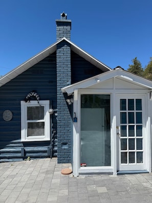 A house with a blue exterior, a white door with glass panels, and a brick chimney.