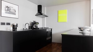 A modern kitchen with a black island, a coffee machine, and a stove. - Hoffman Square - Two Bedroom Apartment, Sleeps 4 (London)