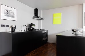 A modern kitchen with a black island, a coffee machine, and a stove. - Hoffman Square - Two Bedroom Apartment, Sleeps 4 (London)