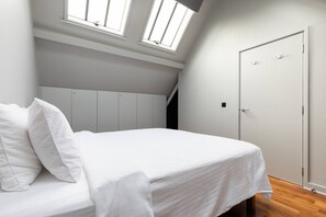 A bedroom with a bed, a wardrobe, a door, and skylights. - Hoffman Square - Two Bedroom Apartment, Sleeps 4 (London)