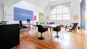 A spacious conference room with a high ceiling, a large window, and a modern design. - Hoffman Square - Two Bedroom Apartment, Sleeps 4 (London)