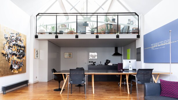A modern loft-style living space with a dining area, kitchen, and a mezzanine level with plants. - Hoffman Square - Two Bedroom Apartment, Sleeps 4 (London)