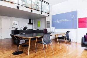 A modern kitchen with a dining area, featuring a large wooden table, black chairs, and a kitchen island with appliances. - Hoffman Square - Two Bedroom Apartment, Sleeps 4 (London)