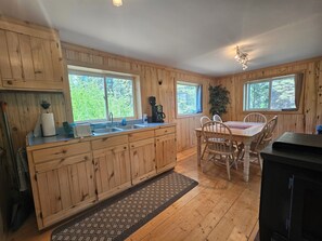 Een houten cabin met een keuken, eethoek en grote ramen.