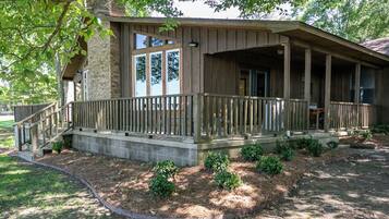 A wooden cabin with a porch, stone foundation, and a small garden area.