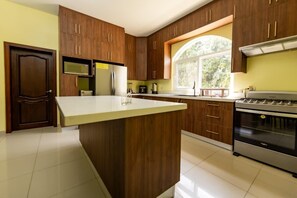 A kitchen with wooden cabinets, a central island, a microwave, a refrigerator, and an oven.