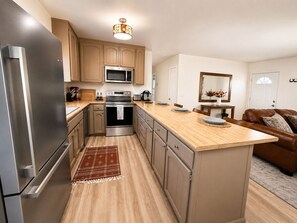 A modern kitchen with stainless steel appliances, wooden cabinets, and a central island.