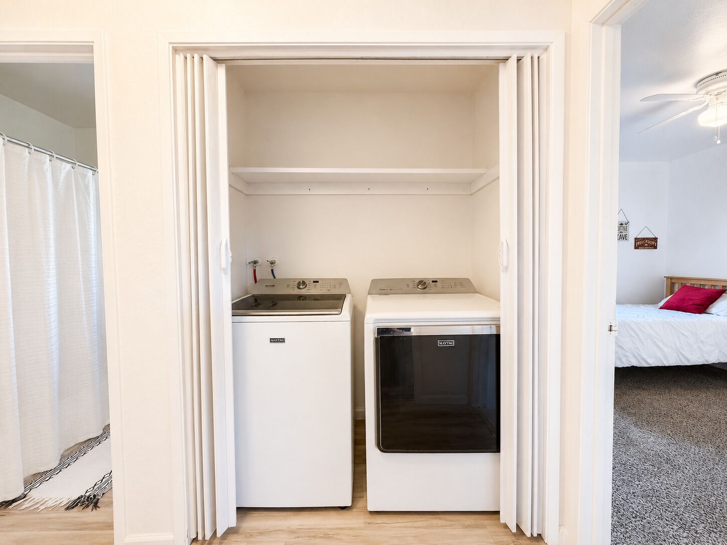 A compact laundry room with a washing machine and dryer, a small sink, and a ceiling fan.