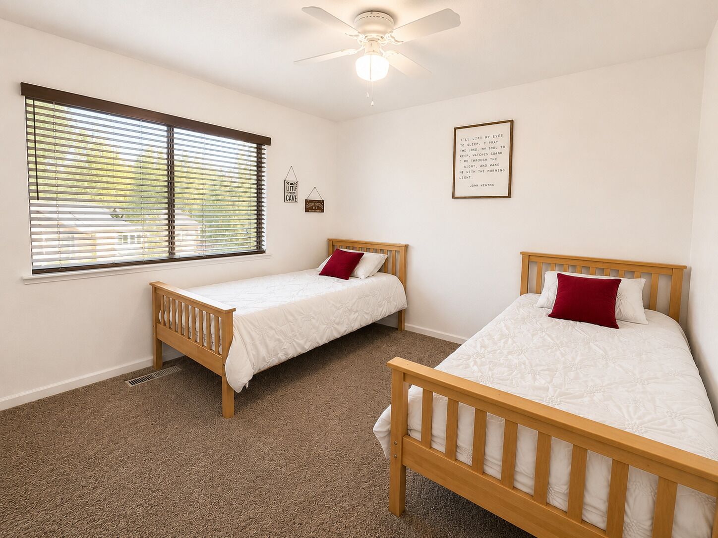 A bedroom with two single beds, a ceiling fan, and a window with blinds.