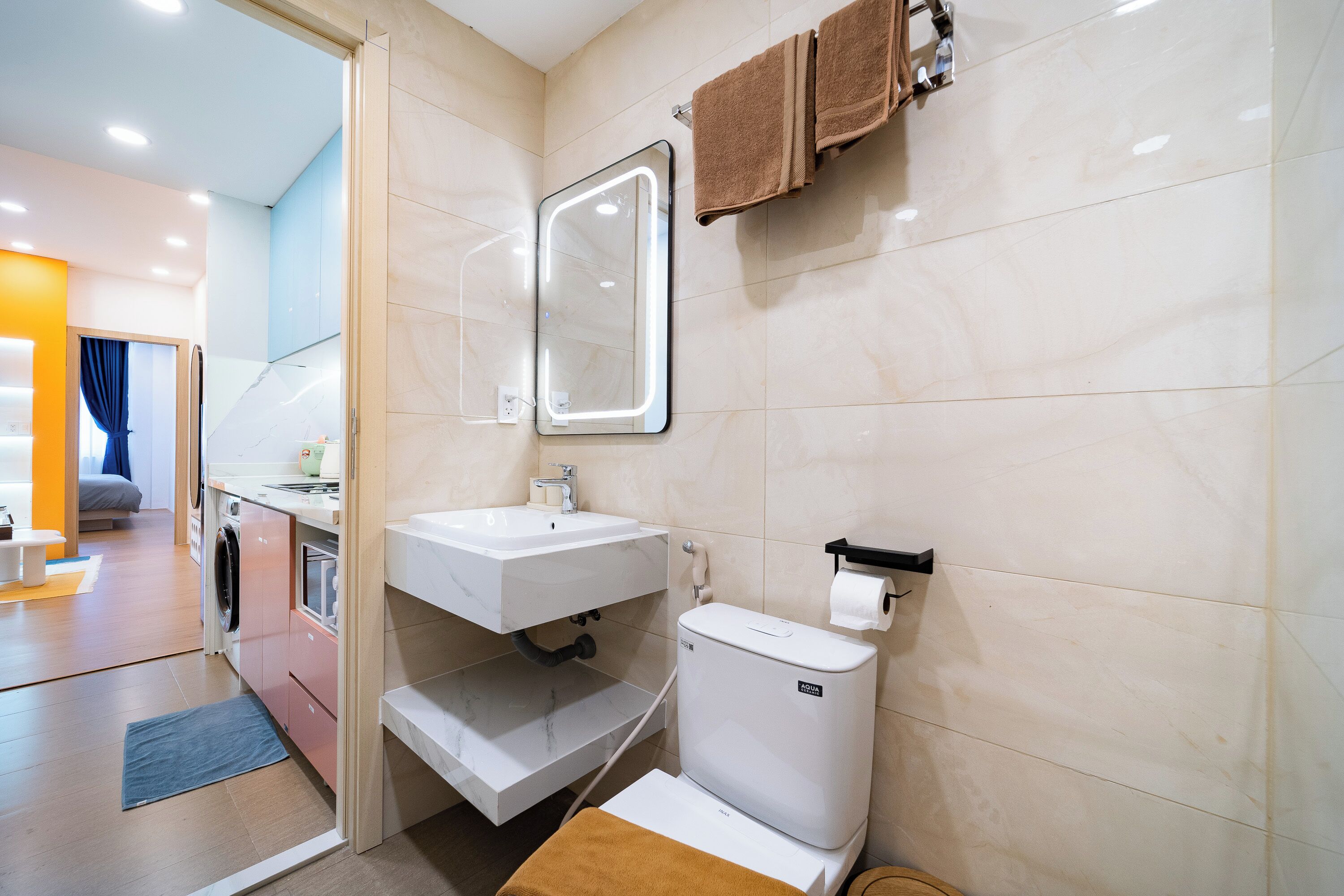 A modern bathroom with a white sink, a mirror, a toilet, and a towel rack.