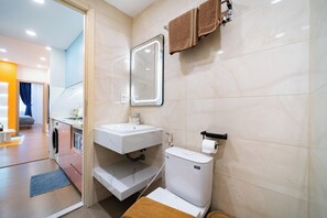 A modern bathroom with a white sink, a mirror, a toilet, and a towel rack.