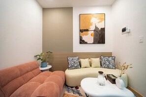 A modern living room with a sofa, a coffee table, and a wall-mounted painting.